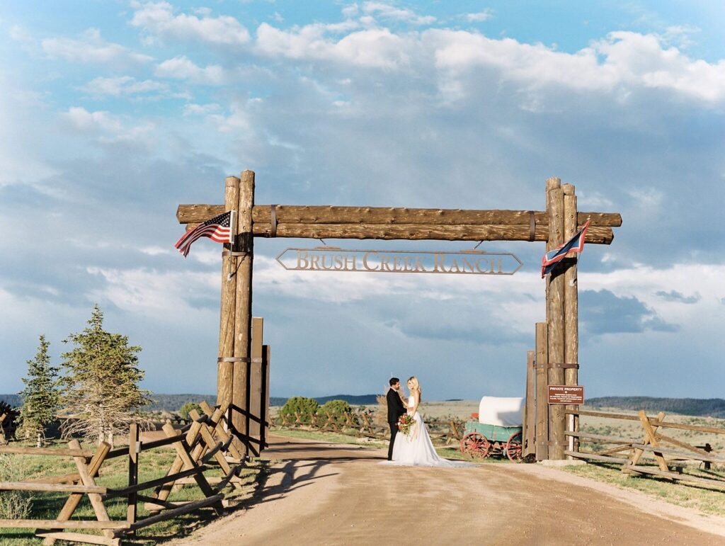 Bride and groom pose under Brush Creek Ranch sign