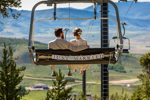 Newlyweds sit on ski lift with Just Married sign