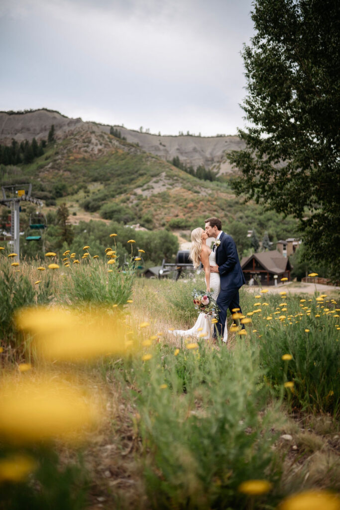 Bride and groom kiss in front of Colorado mountains