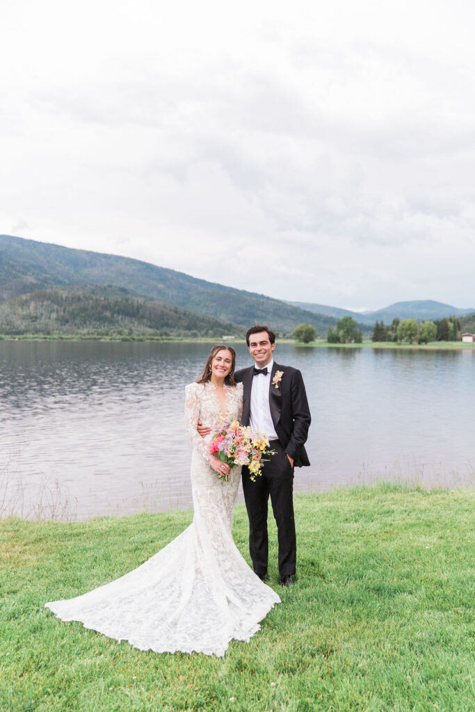 Bride and groom pose by lake in Colorado